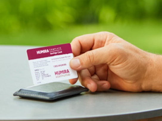 Hand holding HUMIRA Complete savings card.